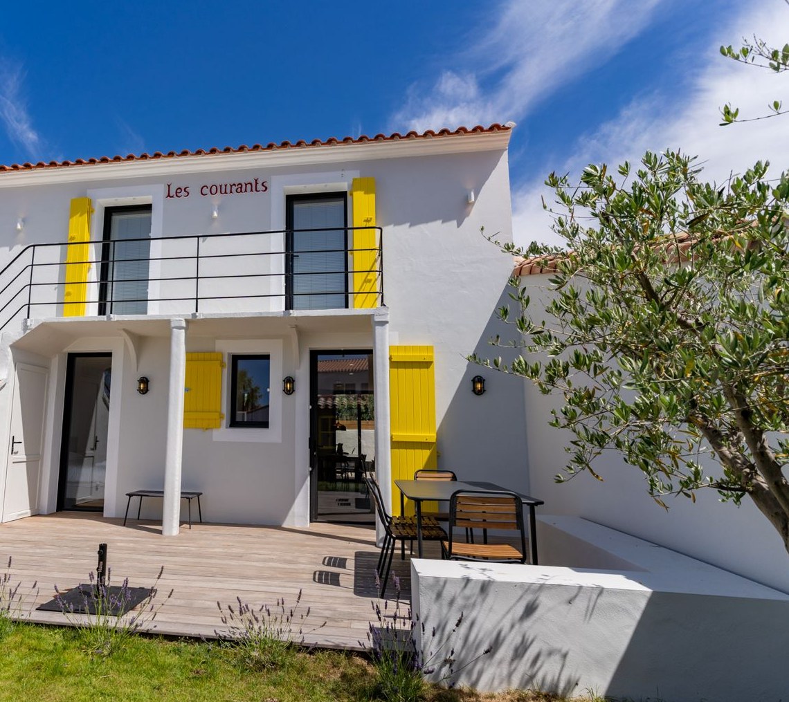 La maison côté terrasse, façade blanche et volets jaunes